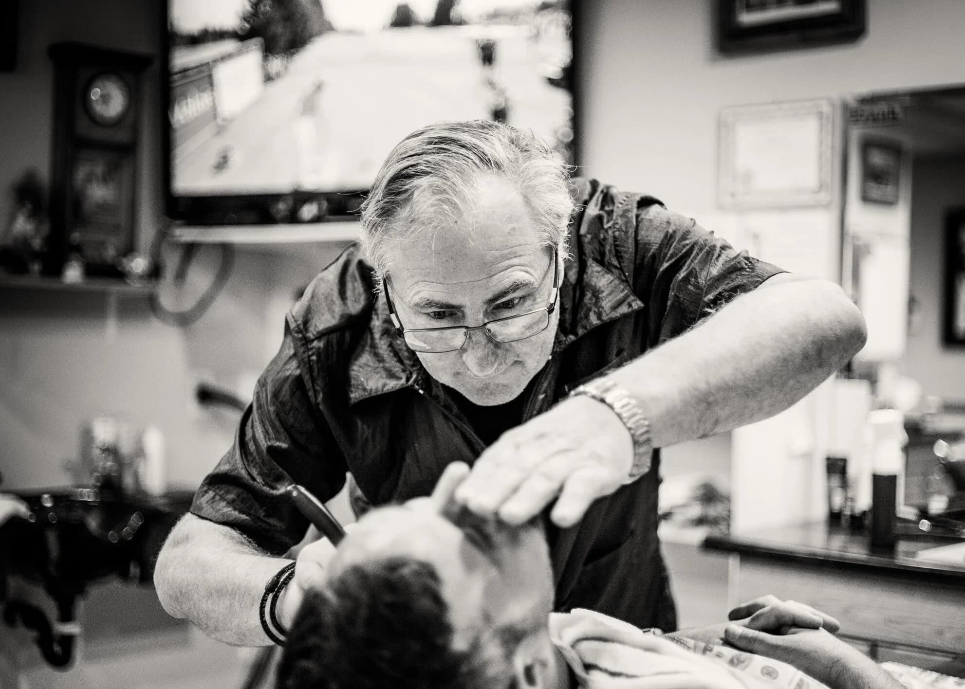 Black-and-white source photograph of the Rooster’s barber at work